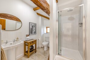 A bathroom with a wooden beam ceiling, a large mirror, a sink, a toilet, and a glass-enclosed shower. - 4 Bed in Rhayader (oc-c46317) (Rhayader)