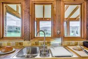 A kitchen with a large window, a stainless steel sink, and a cutting board. - 4 Bed in Rhayader (oc-c46317) (Rhayader)