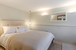 A bedroom with a bed, a wall-mounted light, and a mirror. - 1 Bed in Blakeney (oc-a46334) (Blakeney)