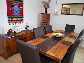 A dining area with a wooden table, black leather chairs, a vase with flowers, and a mirror on the wall. - 4 Bed in Kirkcudbright (oc-d546533) (Kirkcudbright)