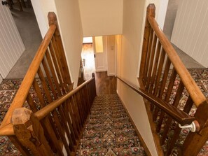 Eine Holztreppe mit einem gemusterten Teppich, der zu einem Raum führt.
