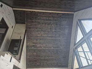 Ein Zimmer mit schrägem Dach, Holzvertäfelung und einem großen Fenster.