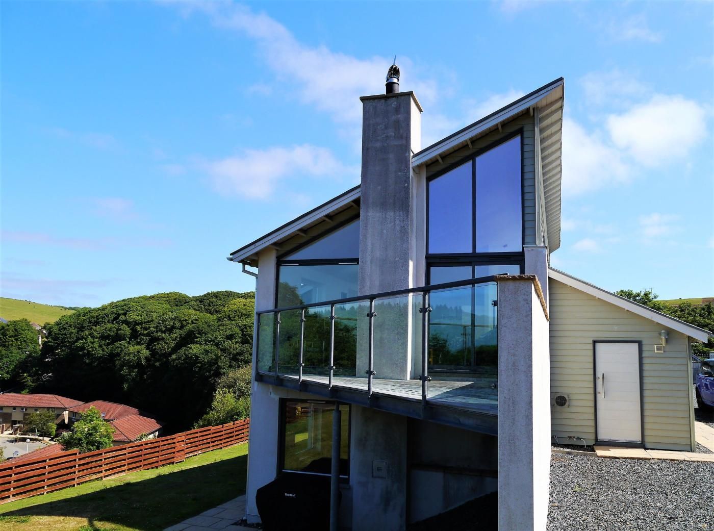 A modern two-story house with a prominent chimney, large windows, and a visible garage.