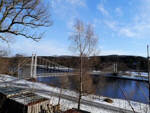 Eine Hängebrücke über einem Fluss, mit Schnee bedeckter Boden.