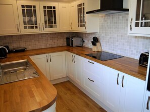 A kitchen with white cabinets, a wooden countertop, a built-in microwave, and a toaster. - 3 Bed in Dalbeattie (oc-d582562) (Portling)