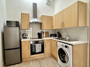 A compact kitchen with a built-in oven, microwave, and washing machine. - 2 Bed in Glentrool, Newton Stewart (oc-d616822) (Glentrool)
