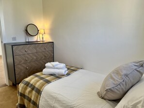 Un dormitorio con una cama, un tocador, un espejo y una lámpara.