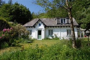 Ein weißes Cottage mit Satteldach, einer Haustür und einer kleinen Veranda.