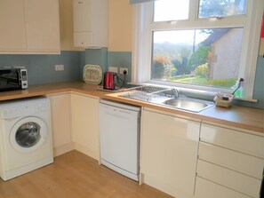 A kitchen with a washing machine, dishwasher, and a window with a view of greenery. - 2 Bed in Dalbeattie (oc-d546078) (Dalbeattie)