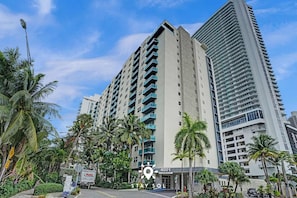 A high-rise hotel with multiple balconies, surrounded by palm trees and other greenery. - Stylish Comfort Elegant APT - Fully Equipped (Hollywood)