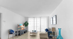 A living room with a sofa, a coffee table, a TV, and a plant. - Stylish Comfort Elegant APT - Fully Equipped (Hollywood)