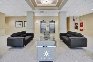 A lobby with two black sofas, a glass-top table, and a 'Stay Sol' sign. - Stylish Comfort Elegant APT - Fully Equipped (Hollywood)
