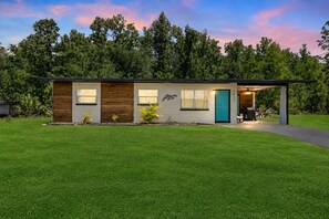 Una casa moderna a un piano con portico anteriore, una porta blu e un garage visibile.