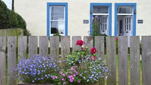 A house with blue-framed windows and a wooden fence in the foreground. - 1 Bed in Carsethorn, Dumfries (oc-d642347) (Carsethorn)