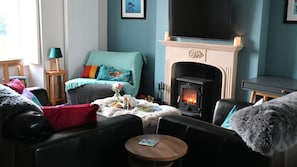 A cozy living room with a fireplace, a sofa, a coffee table, and a television. - 1 Bed in Carsethorn, Dumfries (oc-d642347) (Carsethorn)