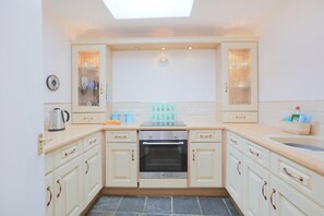 A kitchen with a built-in oven, a kettle, and a coffee maker on the countertop. - 2 Bed in Creetown, Newton Stewart (oc-d586440) (Creetown)