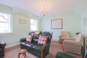 A living room with a green leather sofa, a striped armchair, and a small wooden table. - 2 Bed in Creetown, Newton Stewart (oc-d586440) (Creetown)