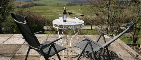 A patio with a table and chairs overlooking a rural landscape.