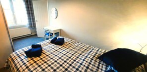 A hotel room with a checkered bedspread, a desk, and a chair. - 2 Bed in Kirkcudbright (oc-d634817) (Kirkcudbright)