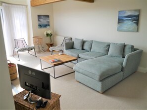 A living room with a sectional sofa, a coffee table, a TV, and a wicker basket. - 3 Bed in Kippford (oc-d611144) (Kippford)