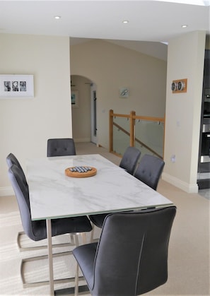 A modern dining area with a marble table, black chairs, and a wooden tray. - 3 Bed in Kippford (oc-d611144) (Kippford)