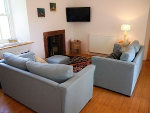 Ein Wohnzimmer mit zwei Sofas, einem Kamin, einem Fernseher und einer Lampe.
