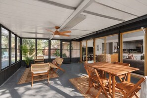Relax in the screened porch with a cozy dining spot and woven seating, fresh air without the bugs. - Southbound Social | Pool • Patio • Games & Movies (Austin)