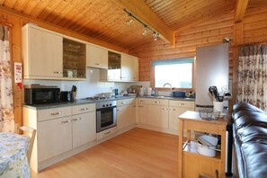 A compact kitchen with wooden cabinets, a microwave, an oven, and a sink. - 3 Bed in Kippford (oc-d574385) (Kippford)