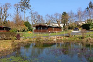 A lakeside property with a wooden cabin, a bridge, and a road. - 3 Bed in Kippford (oc-d574385) (Kippford)