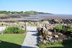 A coastal pathway leading to a rocky beach area with a view of the sea and distant hills. - 4 Bed in Rockcliffe (oc-d585846) (Rockcliffe)