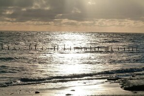 Ein Strand mit Wellen und einem sonnendurchfluteten Himmel.