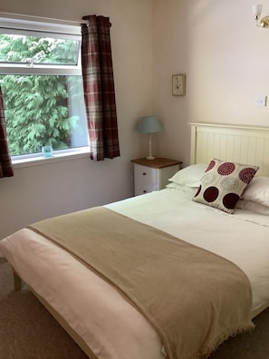 A bedroom with a bed, a nightstand, a lamp, a window with curtains, and a wall-mounted light fixture. - 2 Bed in Lochcarron (oc-d546536) (Lochcarron)