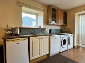 A compact kitchen with a dishwasher, washing machine, and a window above the sink. - 2 Bed in Twynholm, Kirkcudbright (oc-d658490) (Kirkcudbright)