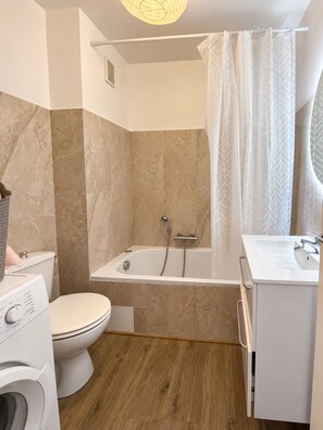 Ein modernes Badezimmer mit Badewanne, Toilette und Waschmaschine.