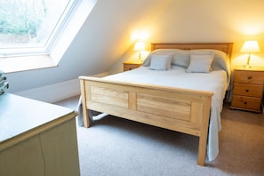 Ein Schlafzimmer mit einem Holzbett, zwei Nachttischen mit Lampen, einem Fenster und einem Schreibtisch.