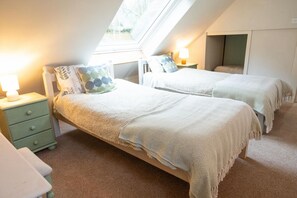 Una camera da letto con due letti, una finestra a soffitto e un comodino con una lampada.