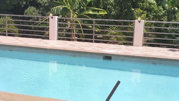 A clear blue swimming pool with a drink in the foreground.