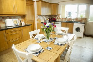 Ein Essbereich mit einem Holztisch, gedeckt für vier Personen, umgeben von weißen Stühlen.