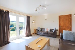 Ein Wohnzimmer mit einer Couch, einem Holztisch und Blick ins Freie.