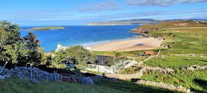 A coastal landscape with a beach, a stone wall, and a grassy area. - 3 Bed in Durness (oc-d545850) (Durness)