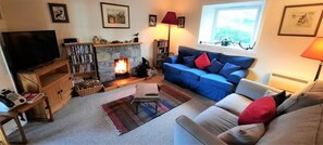 A living room with a fireplace, a television, a sofa, and a bookshelf. - 3 Bed in Durness (oc-d545850) (Durness)