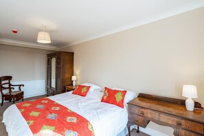 Ein Hotelzimmer mit einem großen Bett, zwei Nachttischen mit Lampen, einem Holzschrank und einem Sessel.