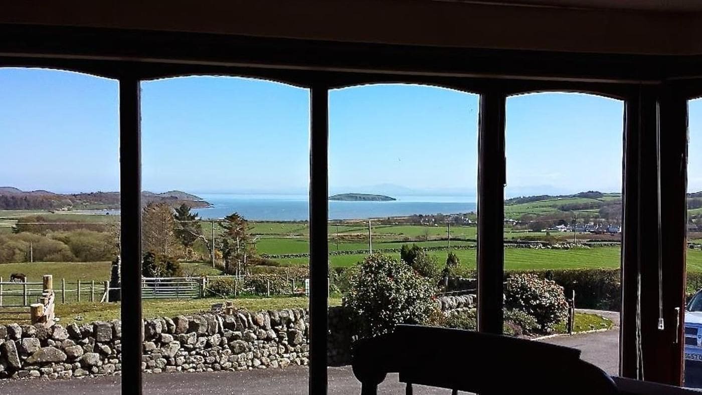 A room with a view of a coastal landscape through large windows.