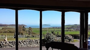 Ein Zimmer mit Blick auf eine Küstenlandschaft durch große Fenster.