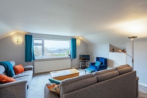 A modern living room with a sofa set, a coffee table, a TV, and a view of the outdoors. - 3 Bed in Rockcliffe (oc-d545917) (Rockcliffe)