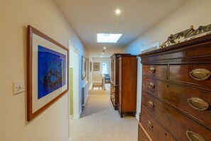A hallway with a skylight, a wooden dresser with brass handles, and framed artwork on the walls. - 8 Bed in New Galloway (oc-d594998) (New Galloway)