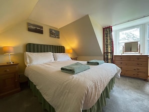 A bedroom with a bed, two bedside tables, a dresser, a window with curtains, and a painting on the wall. - 2 Bed in Grantown On Spey (oc-d546253) (Grantown-on-Spey)