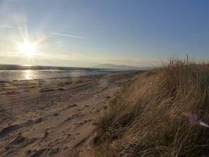A beach with sand and grass, a clear sky, and the sun setting or rising. - 2 Bed in Sandyhills (oc-d546307) (Southwick)