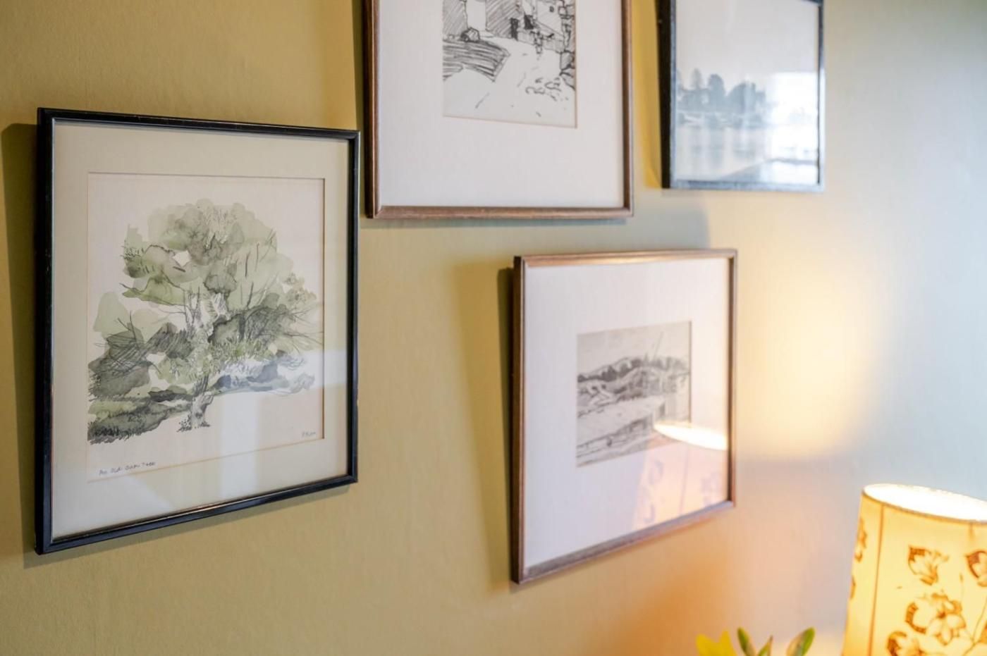 Un mur orné de trois œuvres d’art encadrées, une lampe et une plante.