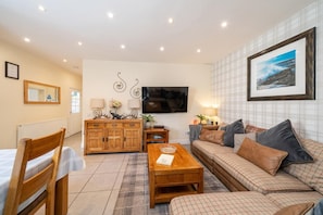 A furnished living room with a sofa, a wooden cabinet, a television, and a framed picture on the wall. - 3 Bed in Crieff (oc-d672592) (Crieff)
